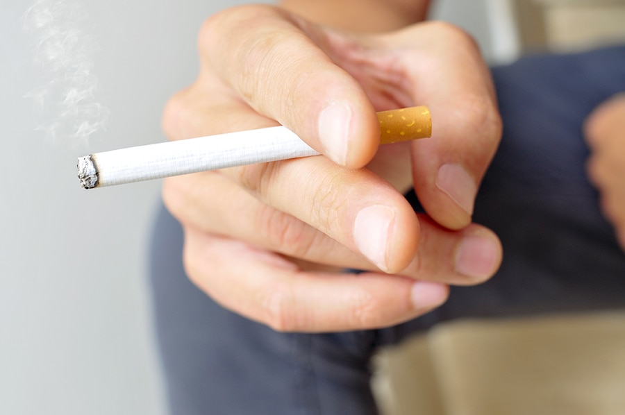 un jeune homme qui fume une cigarette