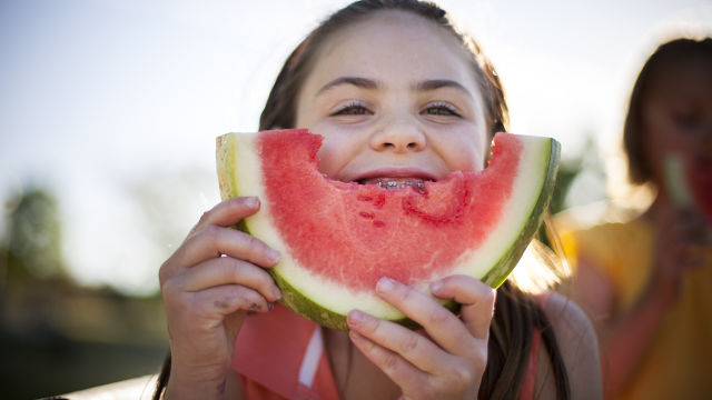 Une petite fille mangeant de la pastèque et souriant à la caméra