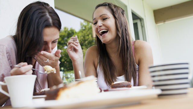 Deux amies riant en mangeant un dessert