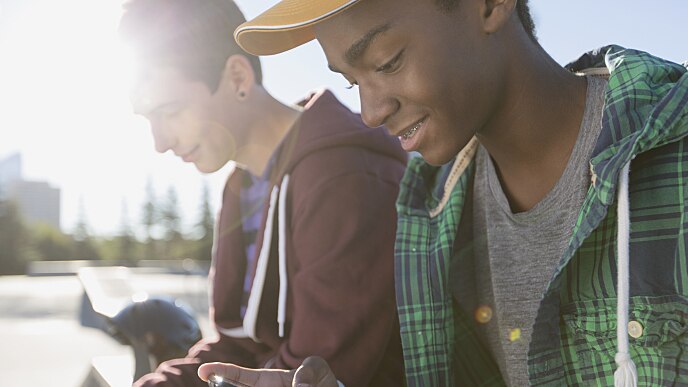 Deux amis regardant leur téléphone portable et souriant