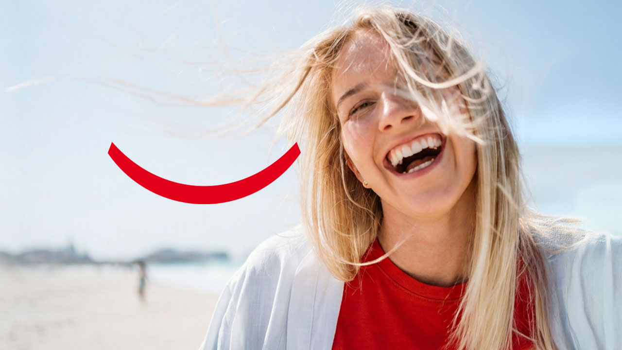 Une jeune femme blonde souriant à l'extérieur avec le vent dans les cheveux, accompagnée du texte « Comment le fluor prévient les caries ».