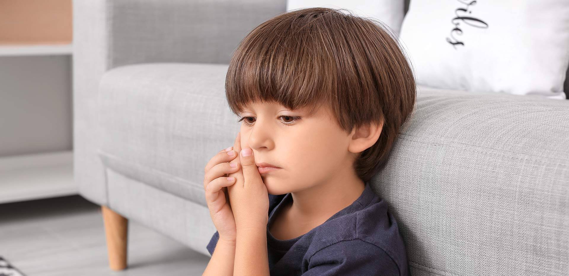 Little boy suffering from tooth ache at home