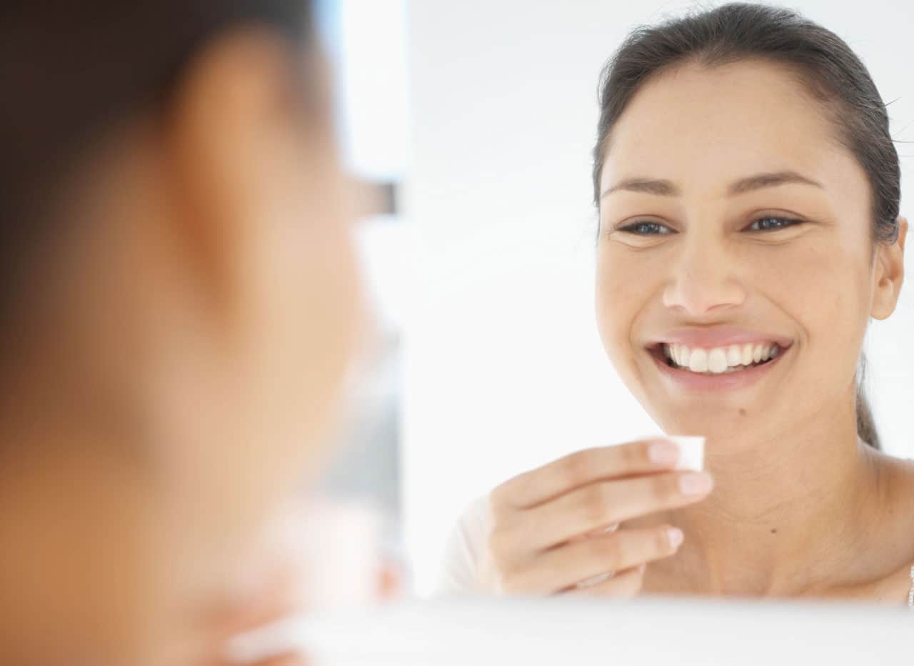 Femme devant un miroire avec solution dentaire liquide dans la main